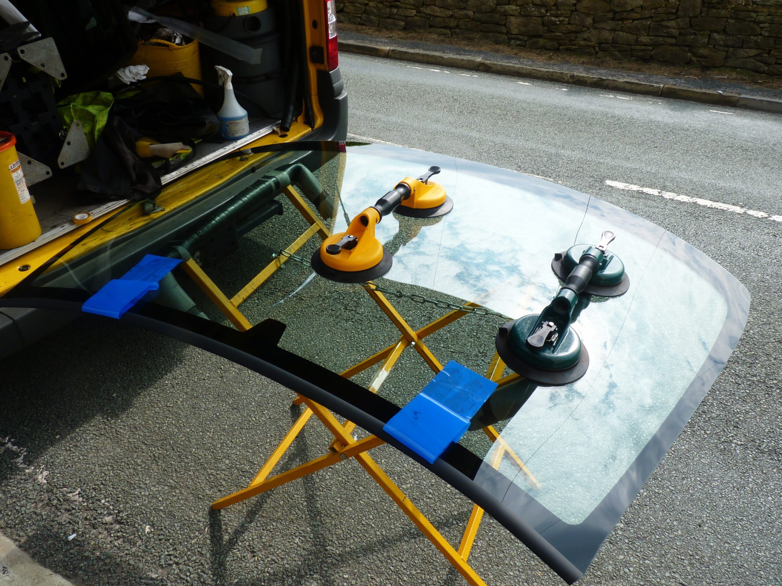 Technician installing car window glass with professional equipment