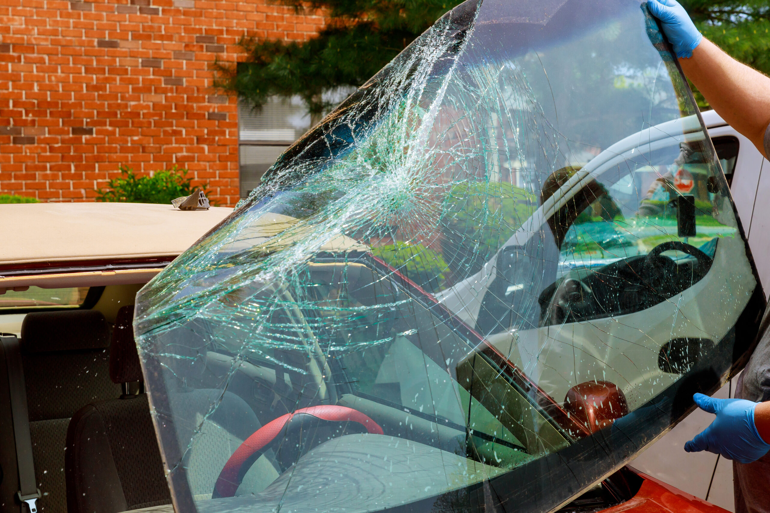 Technician replacing a cracked windshield on a vehicle at an auto glass shop